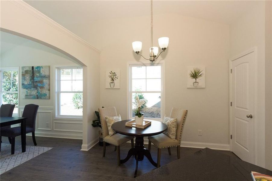 Dining area featuring an inviting chandelier, dark hardwood / wood-style floors, a wealth of natural light, and lofted ceiling