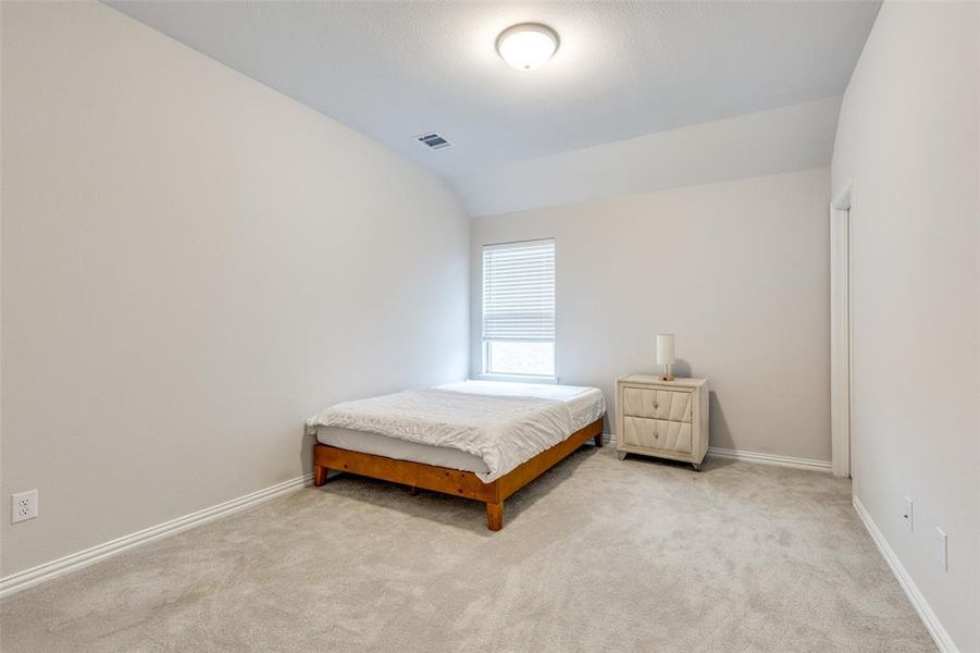 Bedroom with light colored carpet and lofted ceiling