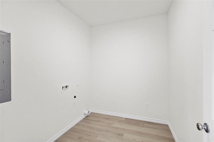 Laundry area featuring light wood-style floors, hookup for an electric dryer, washer hookup, electric panel, and gas dryer hookup Laundry area featuring light wood-style floors, hookup for an electric dryer, washer hookup, electric panel, and gas dryer hookup