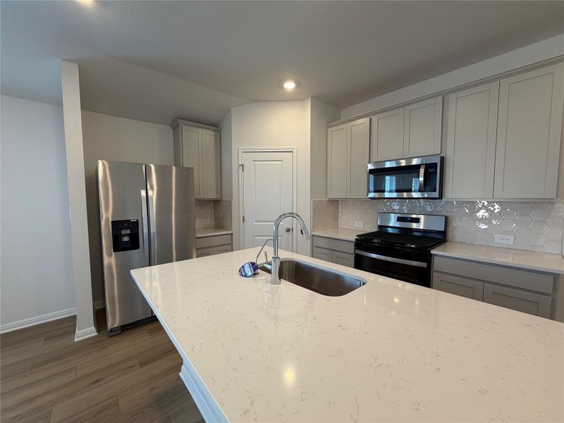 Kitchen featuring gray cabinetry, backsplash, stainless steel appliances, dark wood-type flooring, and recessed lighting