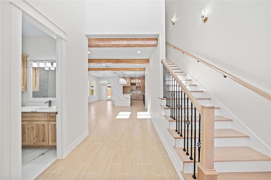 Entrance foyer with wood finish floors, beam ceiling, and a chandelier Entrance foyer with wood finish floors, beam ceiling, and a chandelier