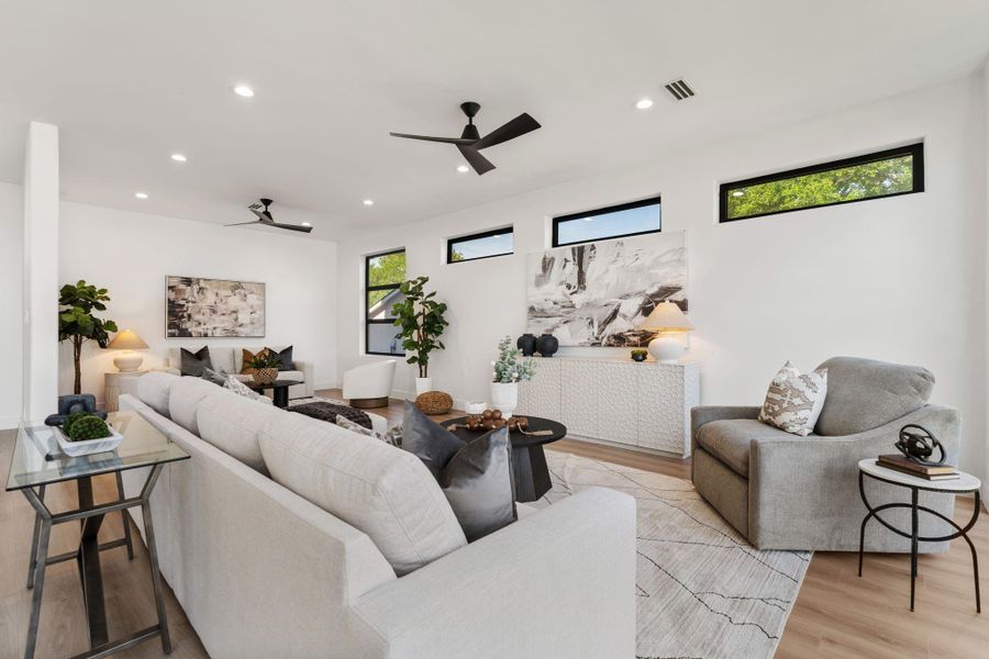 From this angle, the full depth of the living room reveals itself — a space that accommodates a generous seating arrangement and still feels open, with clerestory windows repeating on the far wall to give the room a consistent band of natural light on all sides.