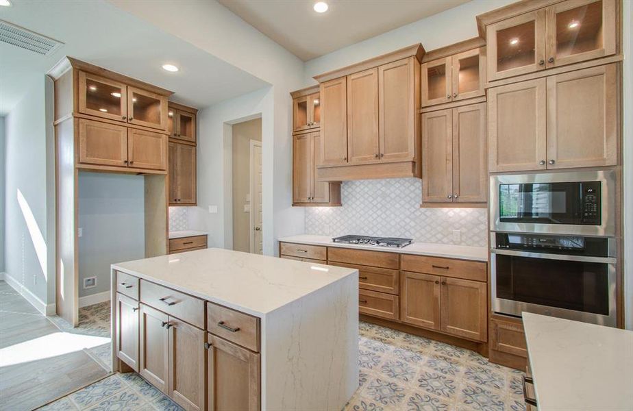 Kitchen with island waterfall granite counter top, upgraded tall cabinets with top and under cabinet lighting.