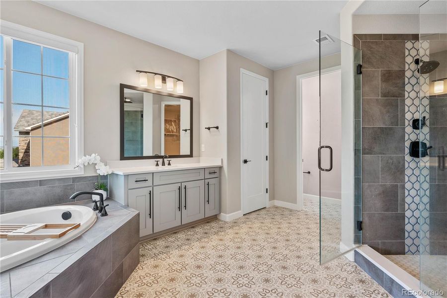 Primary Bathroom with Custom Tiling, Custom Shower, Bathtub, and Dual Vanities.