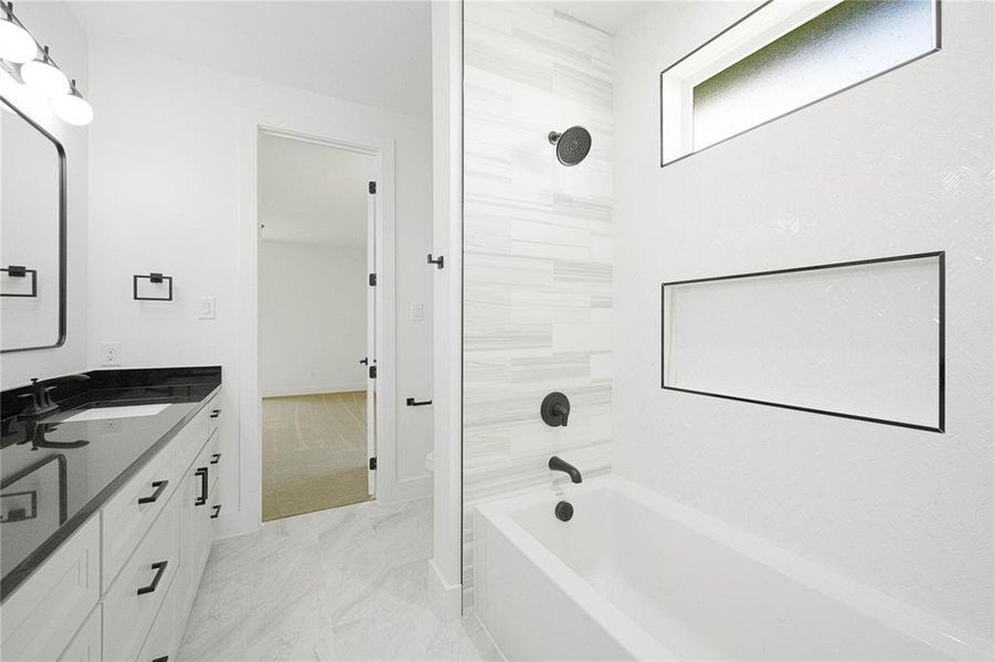 Full bath featuring vanity, tub / shower combination, and light marble finish floors