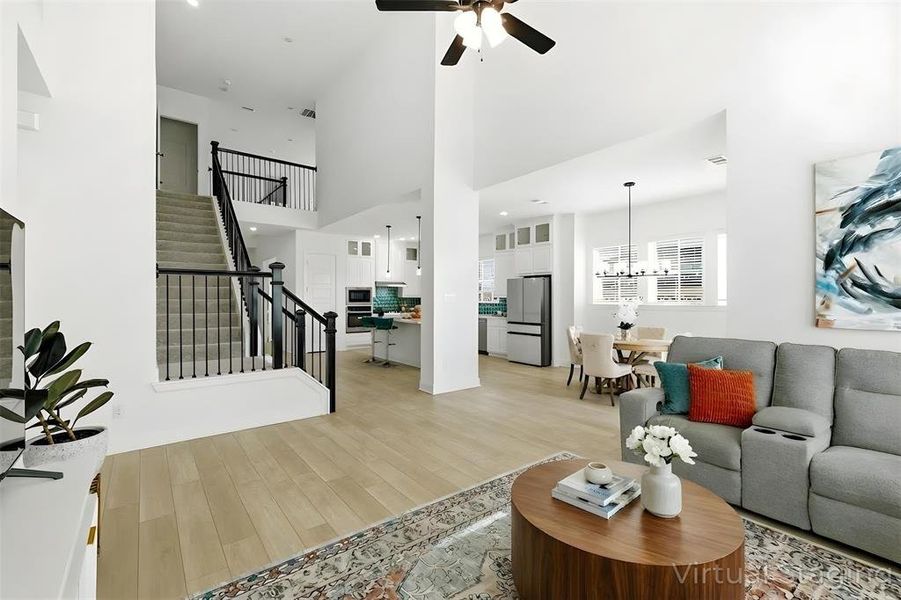 Living area with a high ceiling, light wood finished floors, ceiling fan, and recessed lighting Living area with a high ceiling, light wood finished floors, ceiling fan, and recessed lighting