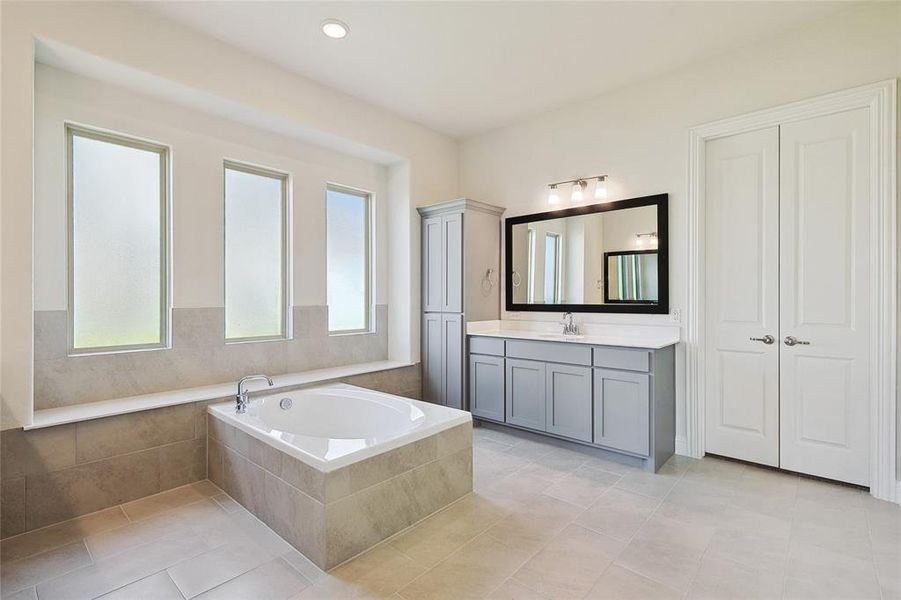 Bathroom featuring tile patterned floors, tiled tub, and vanity