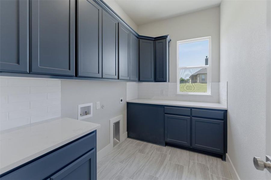 Laundry room featuring shaker-style cabinetry, light-toned countertops, and a white subway tile backsplash