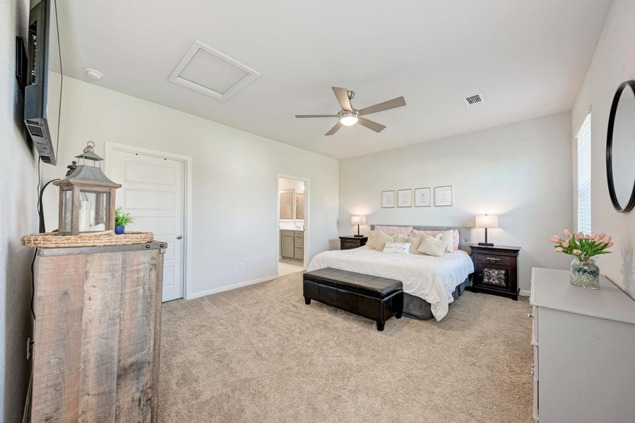 Bedroom with light colored carpet, attic access, ceiling fan, and ensuite bathroom