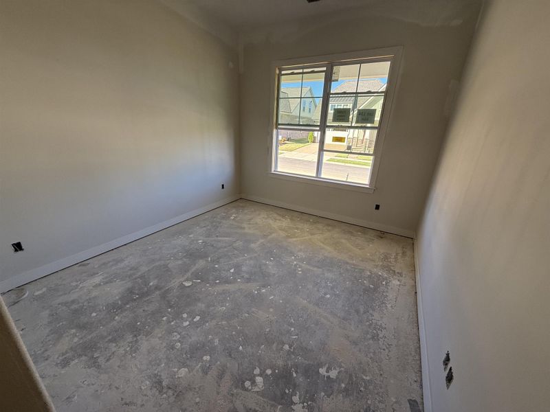 Empty room featuring concrete flooring and baseboards