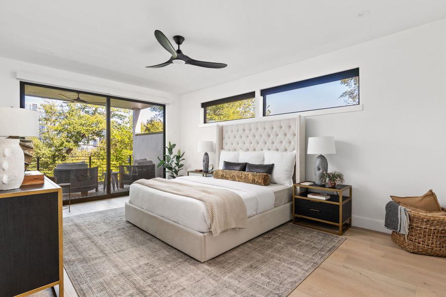 Bedroom featuring wood finished floors, multiple windows, access to exterior, and a ceiling fan Bedroom featuring wood finished floors, multiple windows, access to exterior, and a ceiling fan