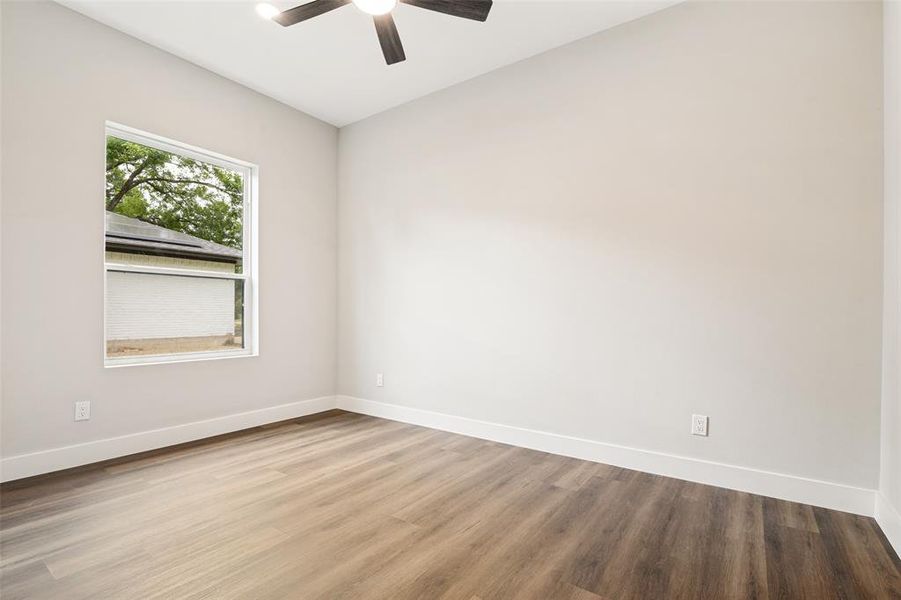 Room featuring wood-finish flooring, a contemporary ceiling fan with integrated lighting, and a window with white trim