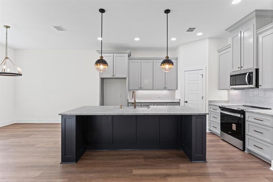 Kitchen featuring a dark-toned island with a light-toned countertop, light-toned cabinetry, and stainless steel appliances
