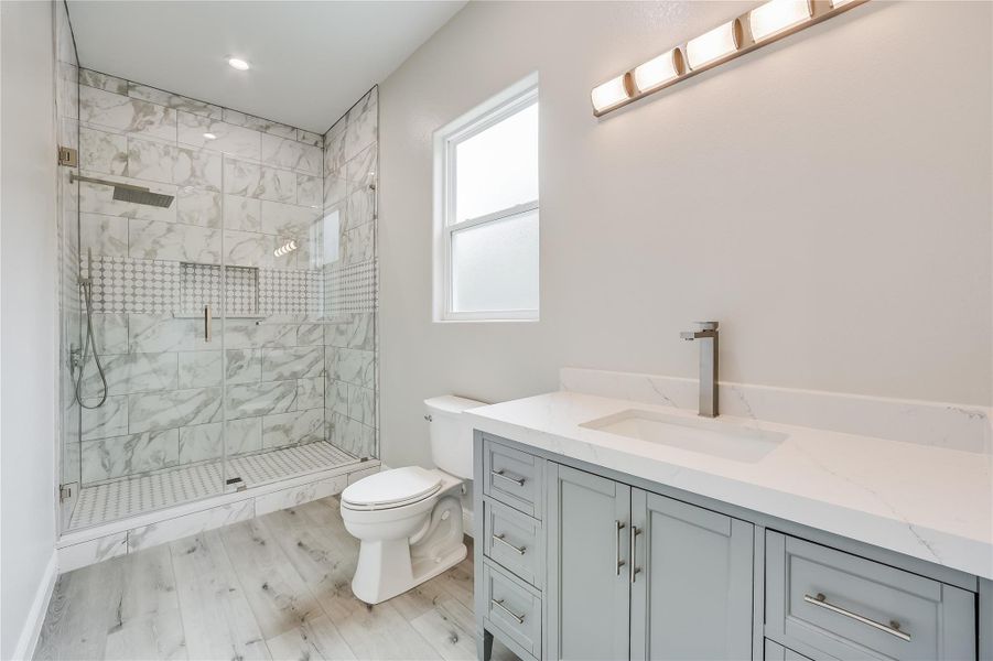 Bathroom featuring hardwood / wood-style floors, an enclosed shower, vanity, and toilet