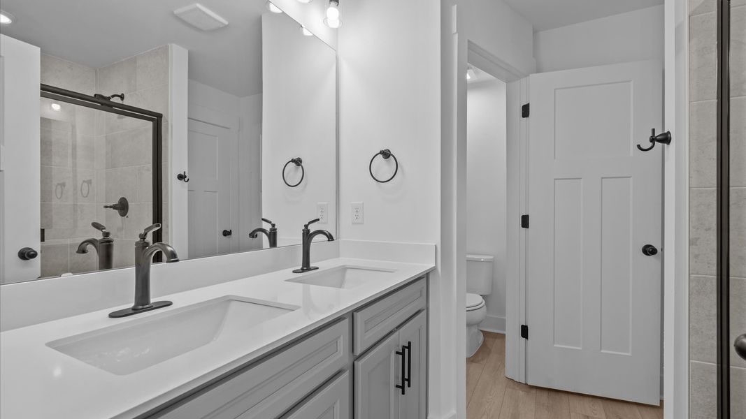 Highly functional and elegant en-suite with dual vanities, tiled walk-in shower, and refined finishes