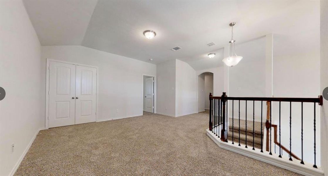 Spare room featuring arched walkways, lofted ceiling, carpet floors, and baseboards