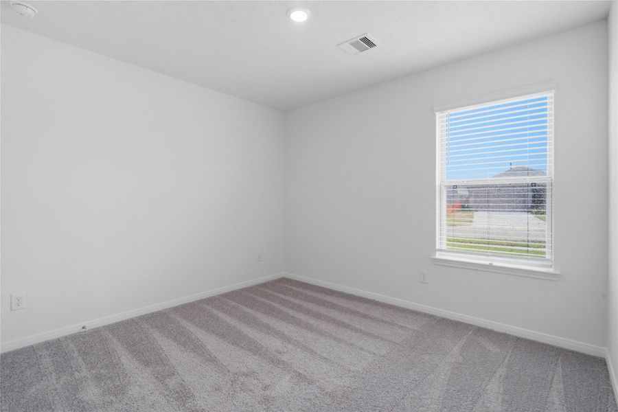 This secondary bedroom offers comfort and style with plush carpeting, neutral paint tones, a large window with blinds, and a generously sized closet.
