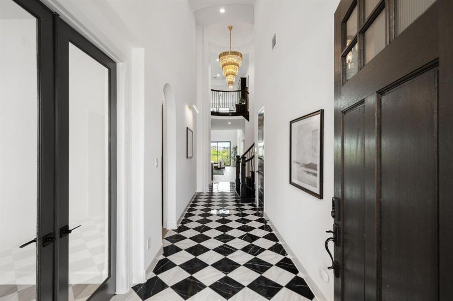 Corridor with a towering ceiling, a chandelier, and recessed lighting Corridor with a towering ceiling, a chandelier, and recessed lighting