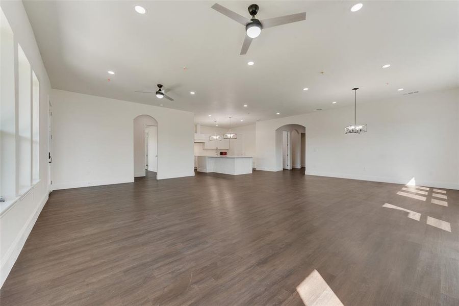 Expansive room with wood-finish flooring, white walls, and recessed lighting Expansive room with wood-finish flooring, white walls, and recessed lighting