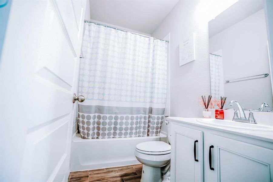 Full bathroom featuring vanity, hardwood / wood-style flooring, toilet, and shower / bath combo with shower curtain