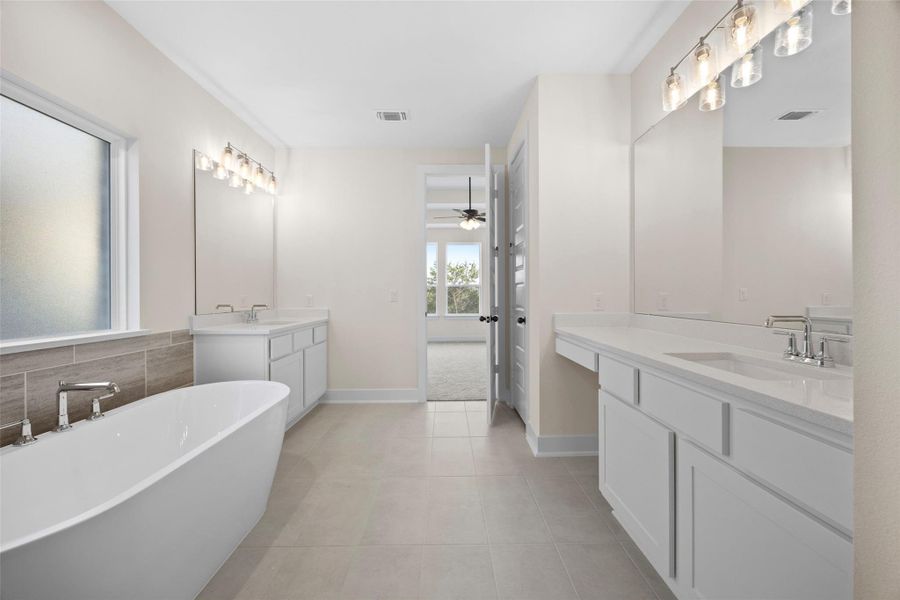 Full bathroom featuring two vanities, a freestanding bath, tile patterned floors, and a ceiling fan Full bathroom featuring two vanities, a freestanding bath, tile patterned floors, and a ceiling fan