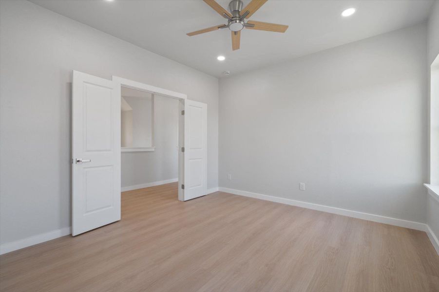 A quiet secondary room, featuring light hardwood floors and a ceiling fan for comfort.