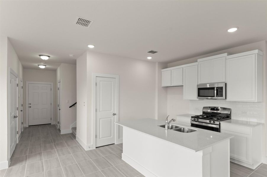 Kitchen with visible vents, appliances with stainless steel finishes, tasteful backsplash, a sink, and white cabinetry