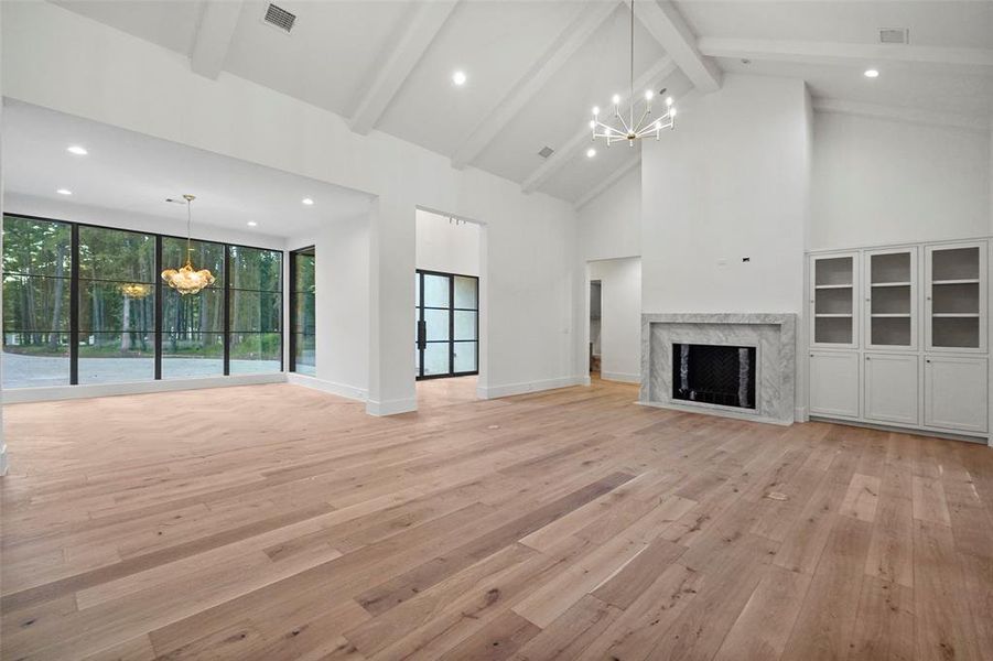 Family room with soaring ceilings, European French Oak floors and 50" wood burning fireplace featuring custom marble surround.