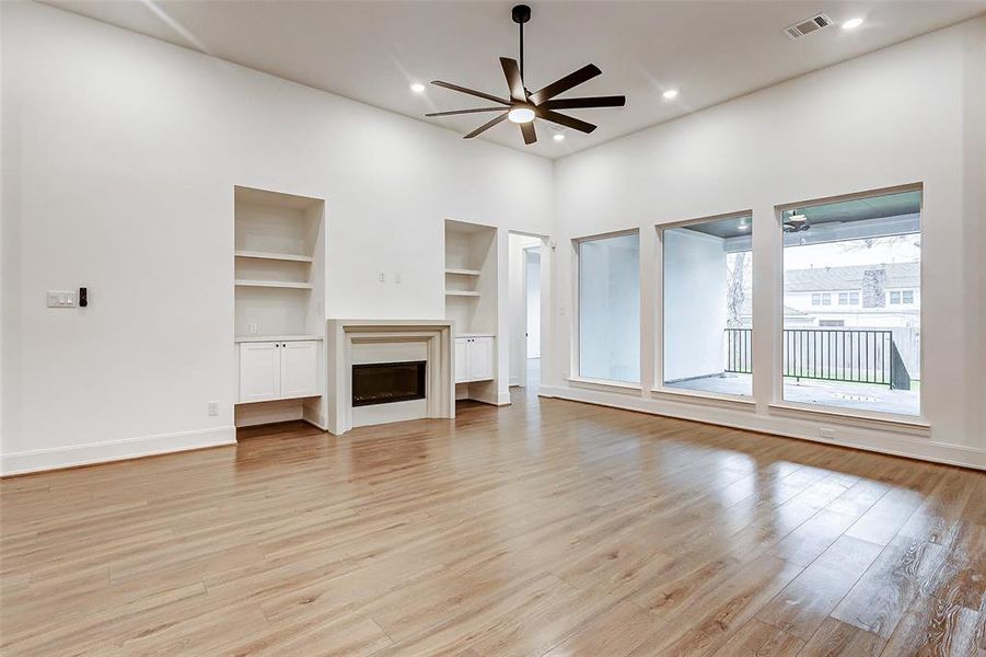 Welcome to your spacious family room! Features include hardwood floors, tall ceilings, recessed lights, a ceiling fan, custom built-is, bright windows, and a fireplace.