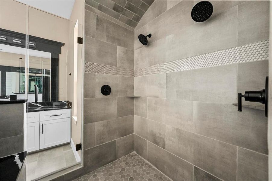 Bathroom with tiled shower, tile patterned flooring, and vanity