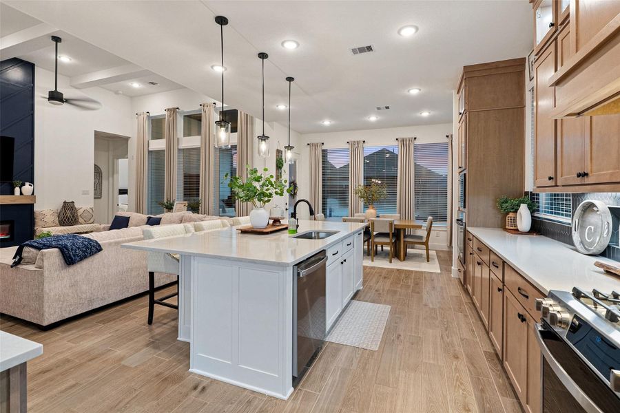 The soaring family room features high ceilings with beams, an electric fireplace wall, and flows into a chef's kitchen with quartz countertops, oversized island, luxe pantry, Barley cabinetry with glass uppers, and GE Profile appliances including double ovens with built-in air fryer. The soaring family room features high ceilings with beams, an electric fireplace wall, and flows into a chef's kitchen with quartz countertops, oversized island, luxe pantry, Barley cabinetry with glass uppers, and GE Profile appliances including double ovens with built-in air fryer.