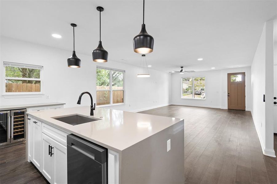 Kitchen featuring decorative light fixtures, wine cooler, dark wood-type flooring, stainless steel dishwasher, and open floor plan