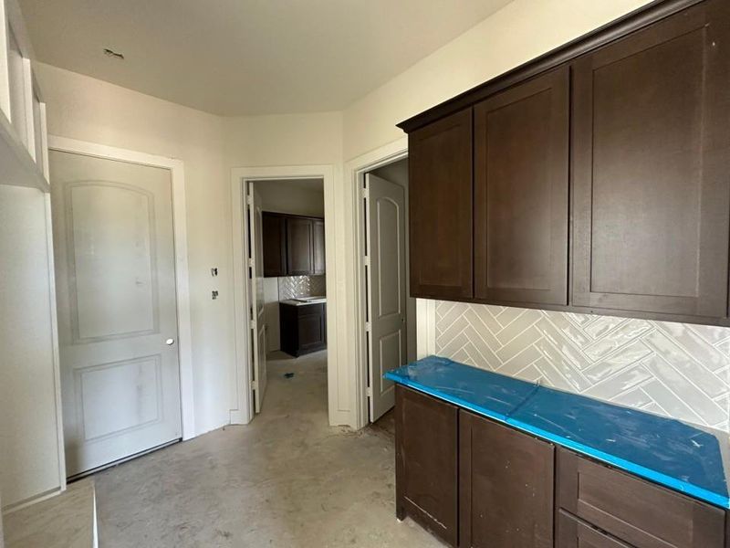 Dark wood-finish cabinetry with crown molding, complemented by a herringbone tile backsplash