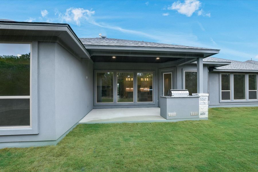 Rear view of property with stucco siding, a yard, and a patio area