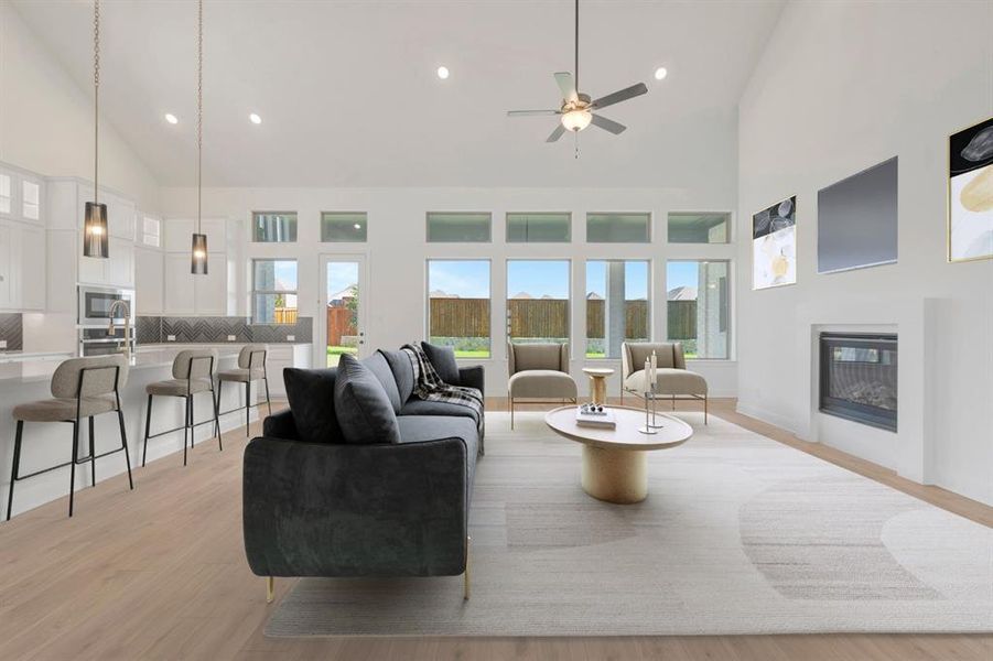 Open-concept living space featuring wood-finish flooring, a contemporary fireplace, and high vaulted ceilings Open-concept living space featuring wood-finish flooring, a contemporary fireplace, and high vaulted ceilings