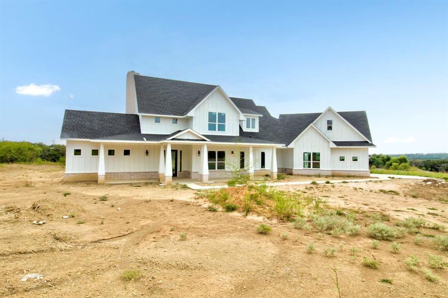 Modern inspired farmhouse with a porch, board and batten siding, and a shingled roof Modern inspired farmhouse with a porch, board and batten siding, and a shingled roof