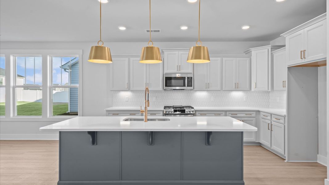 Tasteful design meets functional luxury in this kitchen with a 8-foot island and modern pendant lighting