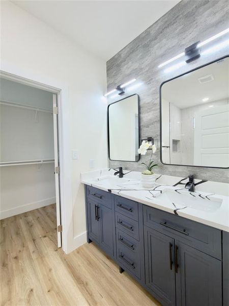 Bathroom featuring a dual vanity with navy cabinetry, white countertops with integrated sinks, matte black faucets, and rectangular mirrors