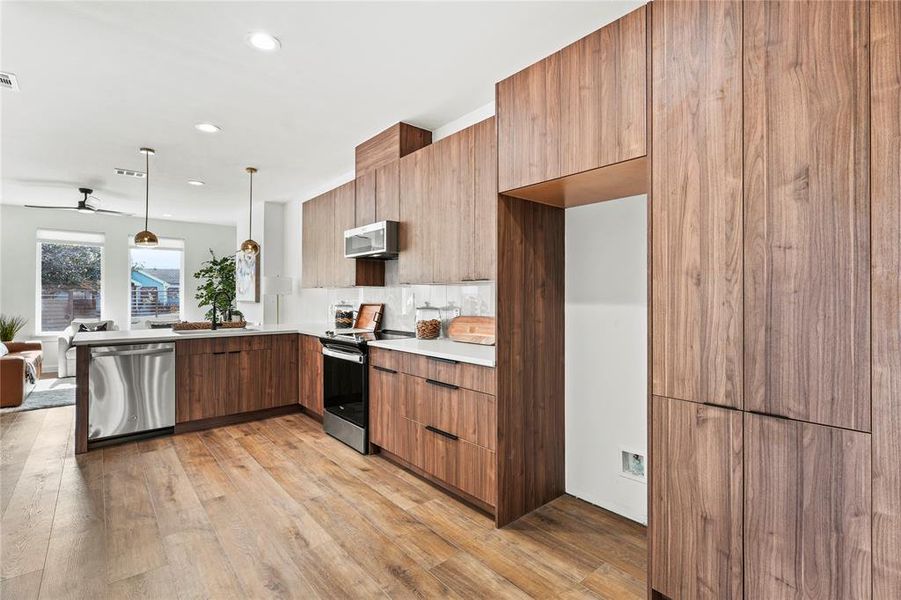 Kitchen with ceiling fan, light hardwood / wood-style flooring, decorative light fixtures, and appliances with stainless steel finishes