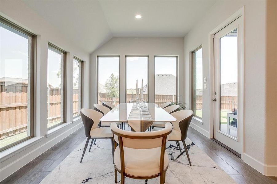 Sunroom / solarium featuring hardwood / wood-style flooring, vaulted ceiling, and baseboards Sunroom / solarium featuring hardwood / wood-style flooring, vaulted ceiling, and baseboards