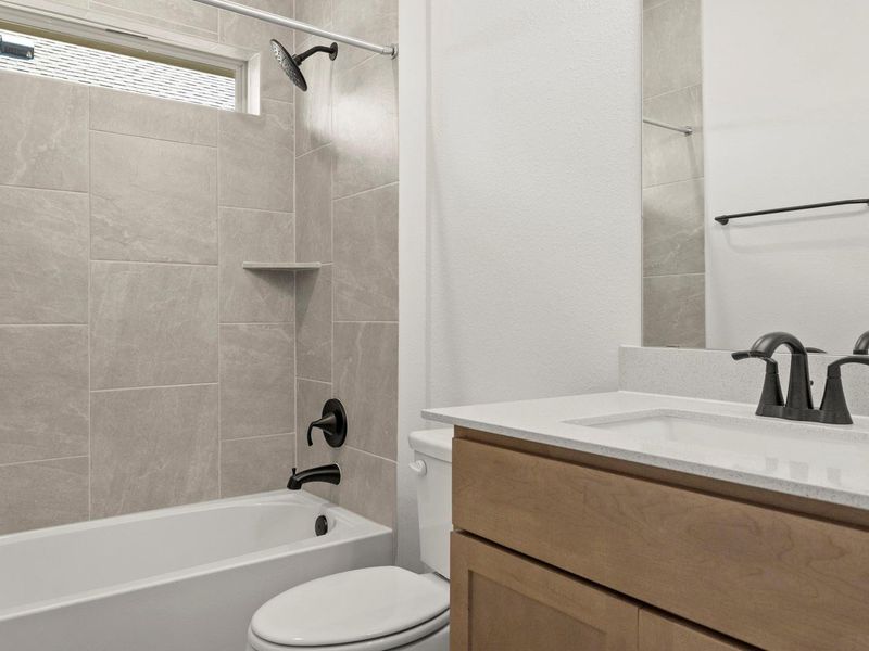 Bathroom featuring a tiled shower surround with a built-in niche, a white tub, and matte black fixtures
