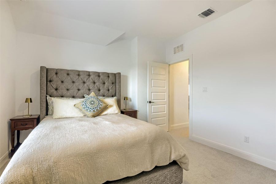 A well-lit bedroom features plush carpet and a stylish tufted headboard, offering a serene retreat. A well-lit bedroom features plush carpet and a stylish tufted headboard, offering a serene retreat.