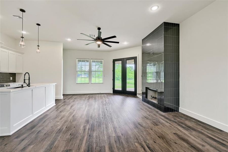 Unfurnished living room with baseboards, ceiling fan, dark wood-style floors, and a sink