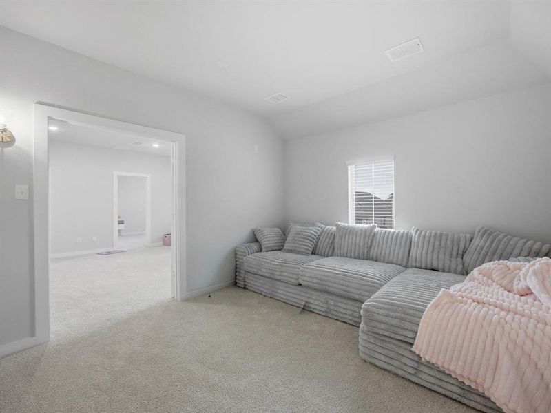 Carpeted living area with lofted ceiling and baseboards