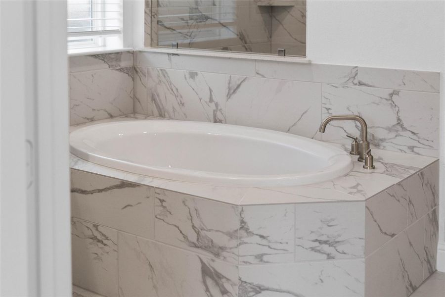 Unwind after a long day in the deep, corner soaking tub, a perfect sanctuary for relaxation. The tub is accented by stylish, warm-toned fixtures.