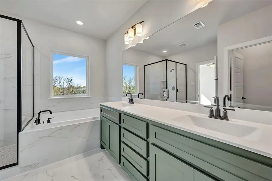 Full bath with double vanity, a marble finish shower, a garden tub, and light marble finish flooring Full bath with double vanity, a marble finish shower, a garden tub, and light marble finish flooring