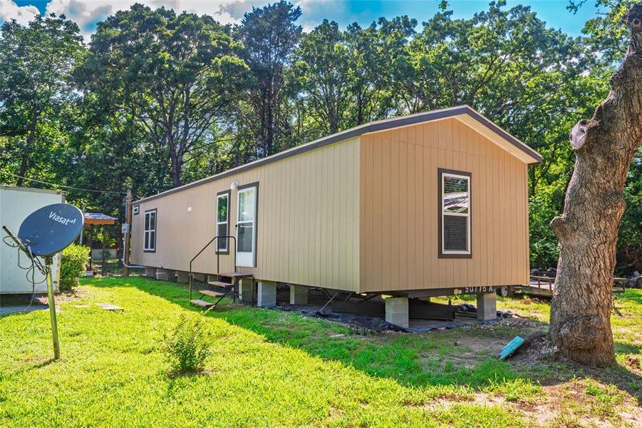 View of side of home featuring entry steps and a lawn