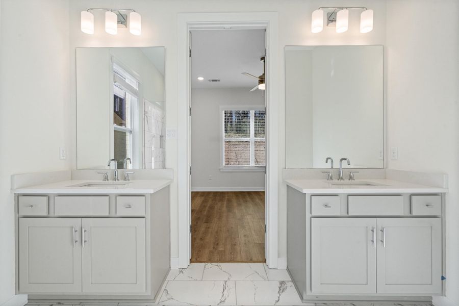 Full bath with a ceiling fan, two vanities, and light marble finish flooring