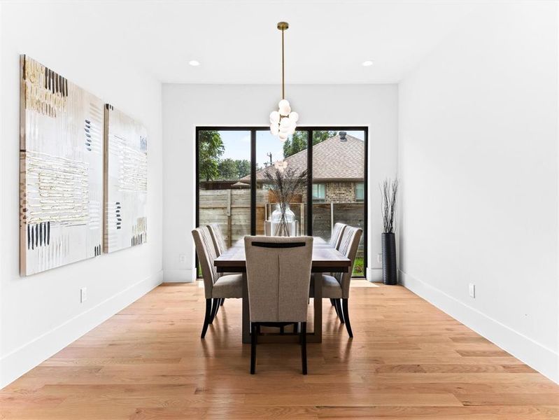 Dining room with light hardwood / wood-style floors and an inviting chandelier