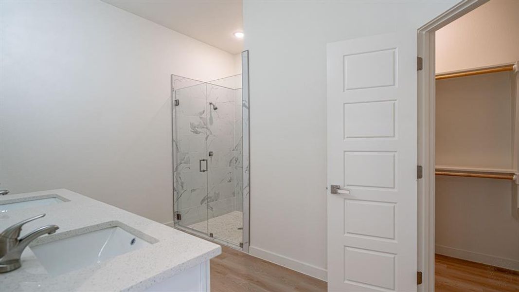 Primary bath with tiled shower, dual sinks and walk in closet
